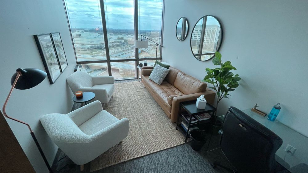 A Dallas Therapy Associates office with boucle chairs, a tan leather sofa, and a downtown view